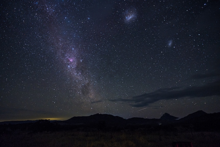 A view of the night sky and the glowing purple Milky Way.