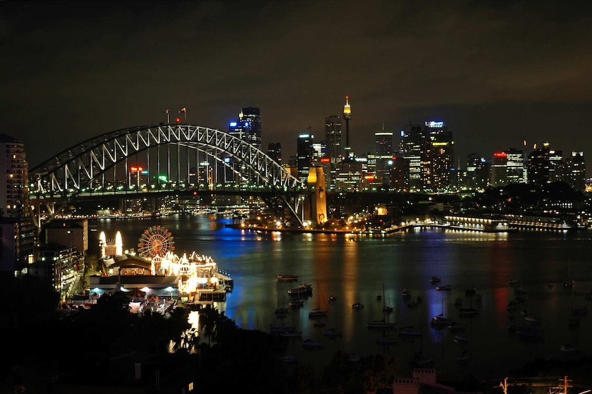 The bright lights of the Sydney Harbor Bridge, the Opera House and the city's skyline create a glowing smoke that envelops the night.