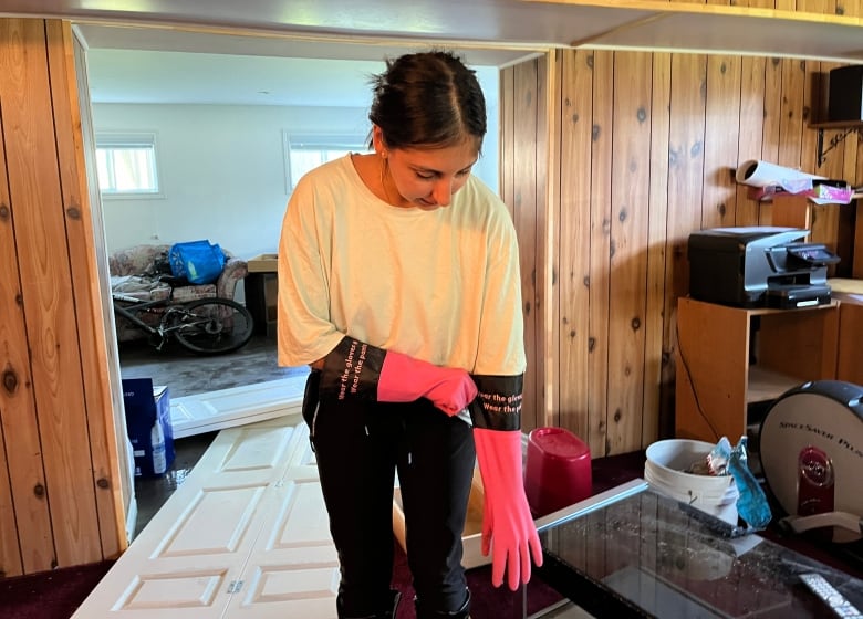 A woman pulls on cleaning gloves